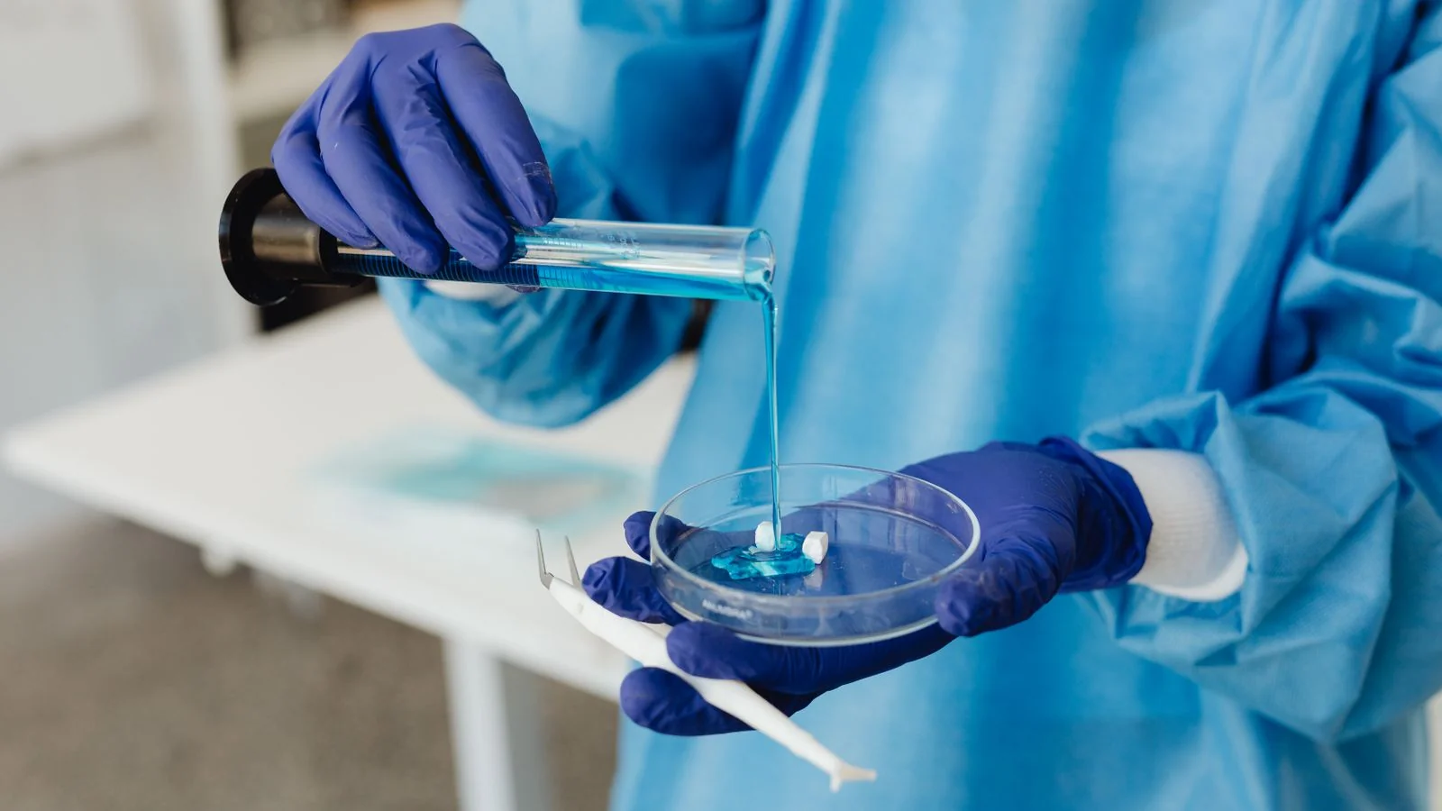 A gloved hand tests a blue liquid sample, part of careful water chemistry work.