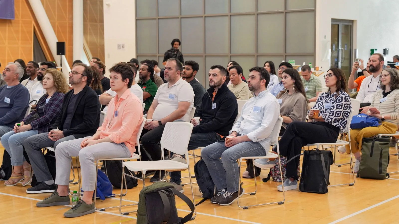 A room of adults listening in an indoor meeting, the planning hearing where a developer's reputation first goes on record.
