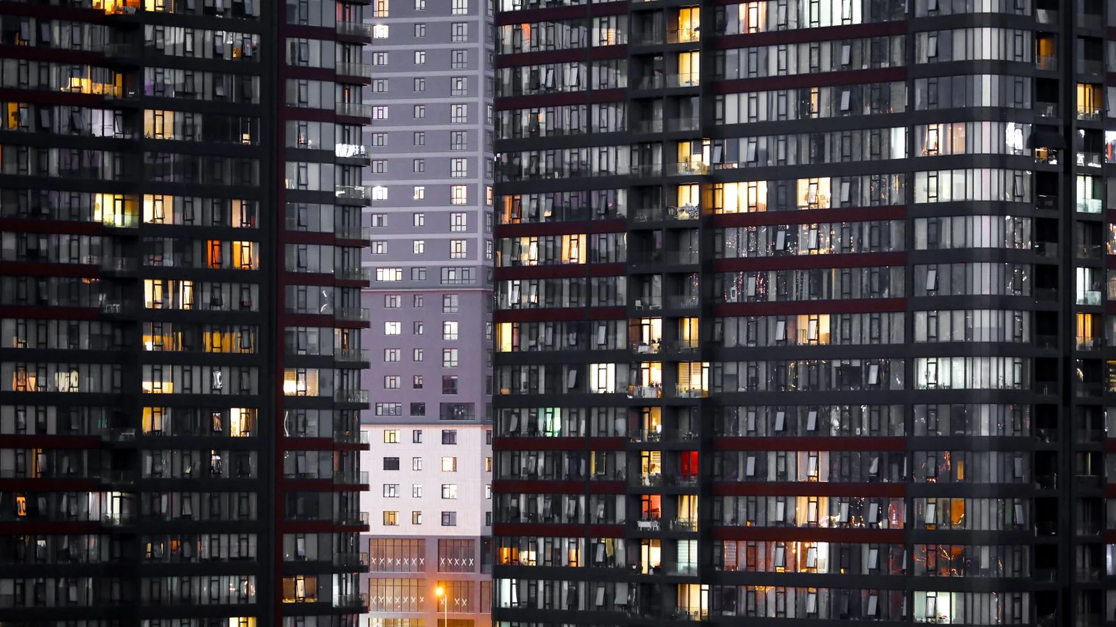 A modern apartment building exterior lit at dusk, the kind property managers lease and maintain
