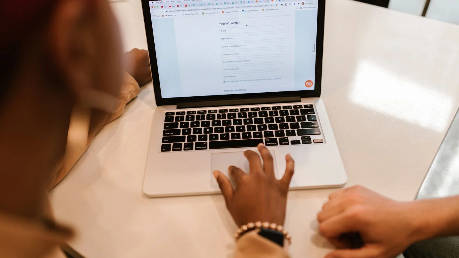 Two people at a laptop filling out an online application form together.