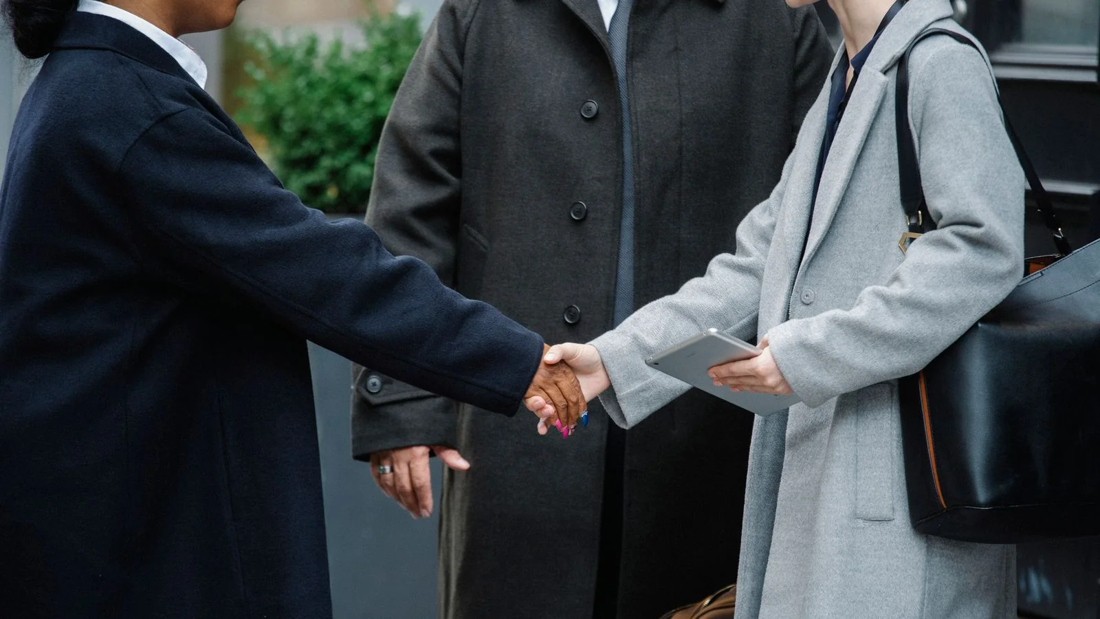 Two people shaking hands on a street after a meeting, the trust a school has to rebuild in public