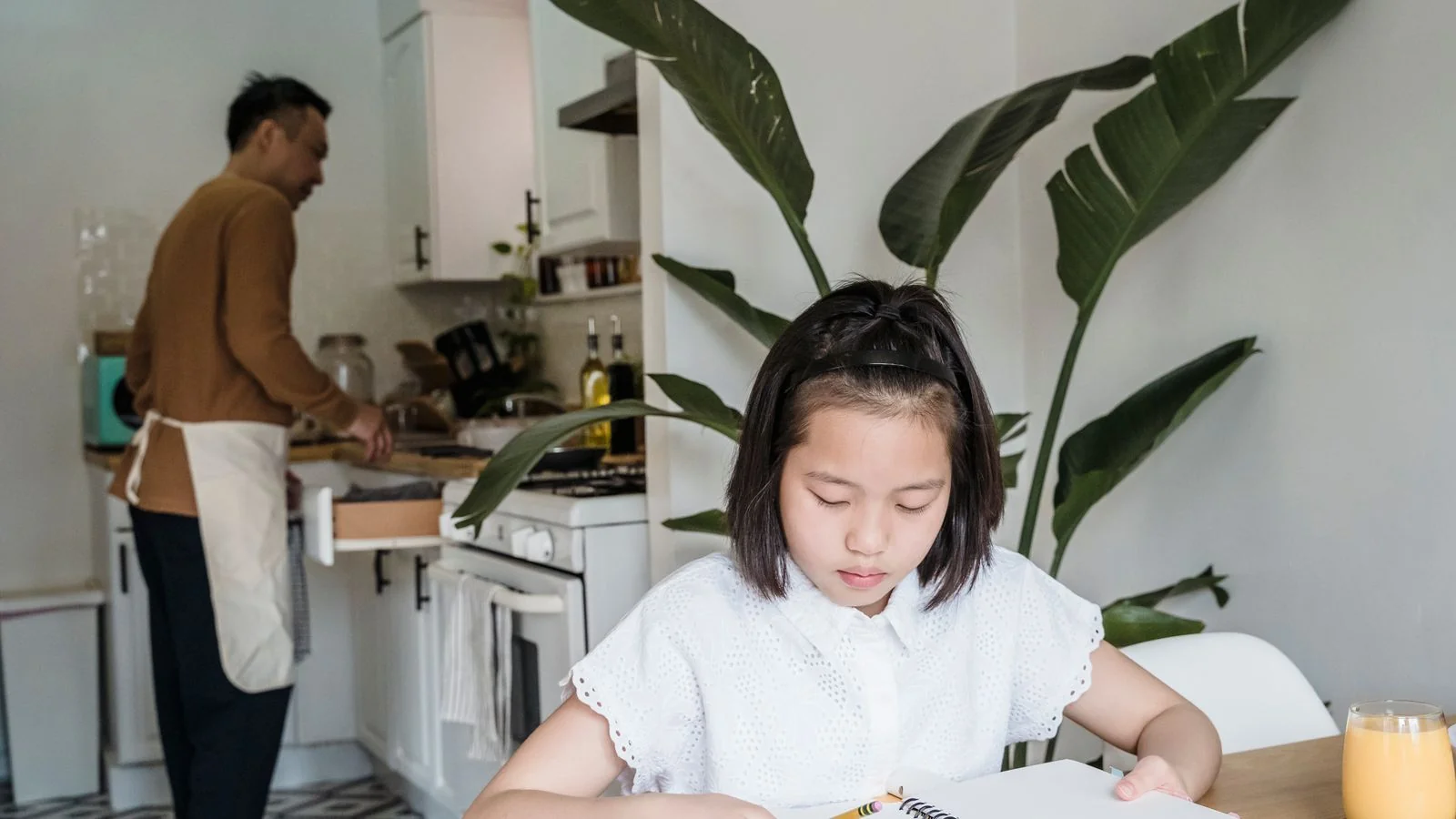 A parent and a child working through homework at a kitchen table
