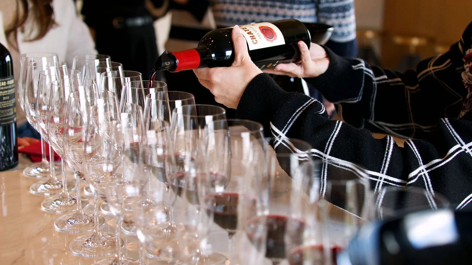 Wine being poured into glasses at a tasting room bar.