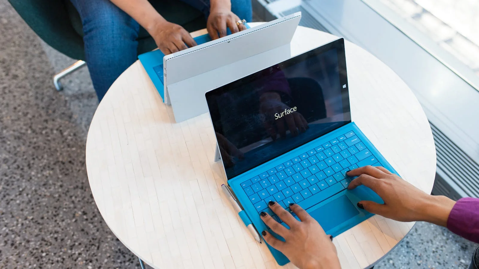 Two colleagues comparing monitoring data across separate laptops in a shared workspace