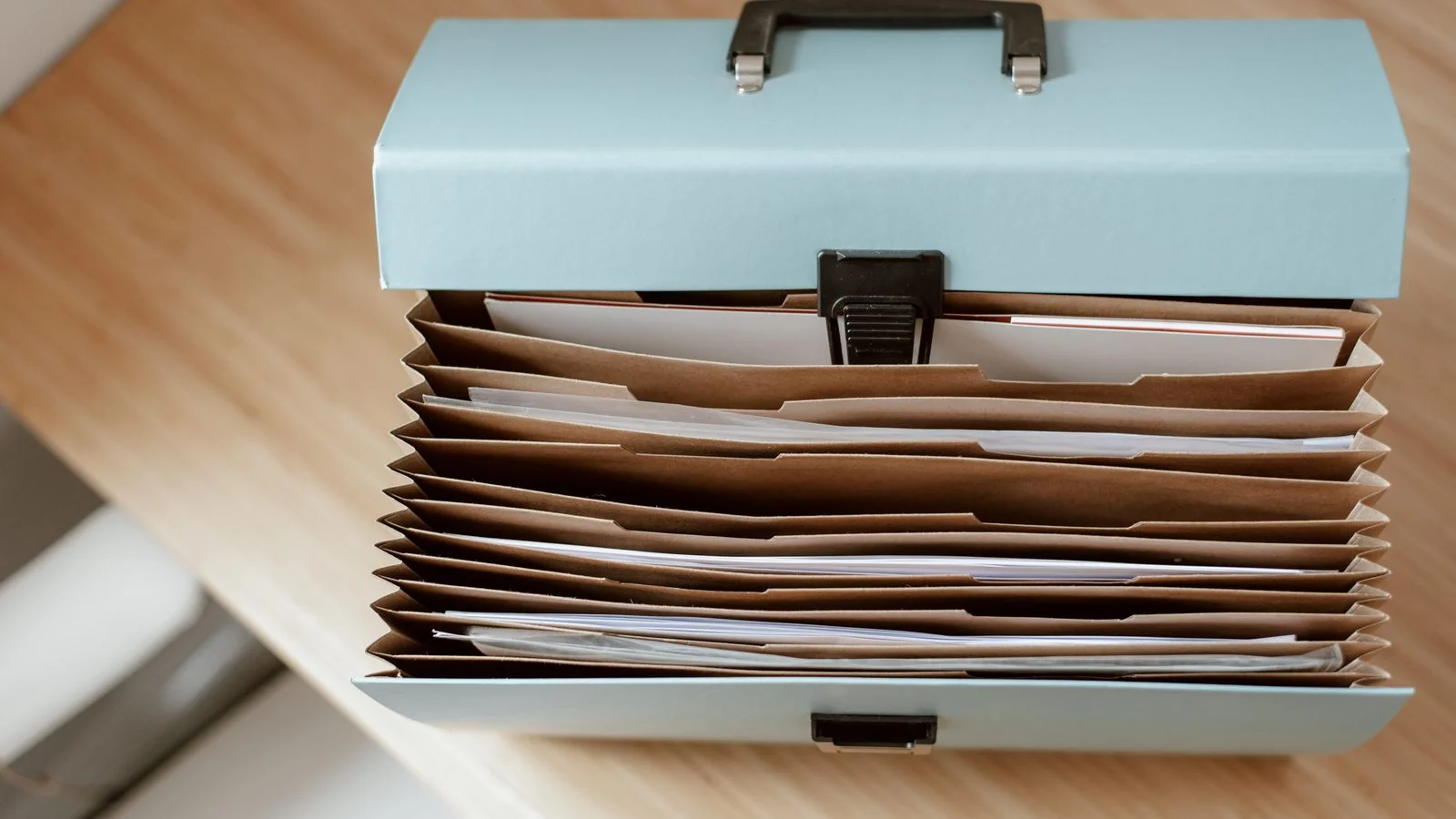Briefcase and loose papers on a wooden table, the kind of personal records data brokers collect