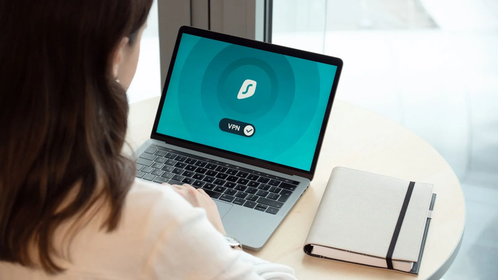 A woman working on a laptop showing a secure browsing icon, the search delisting that reduces discoverability without erasing content