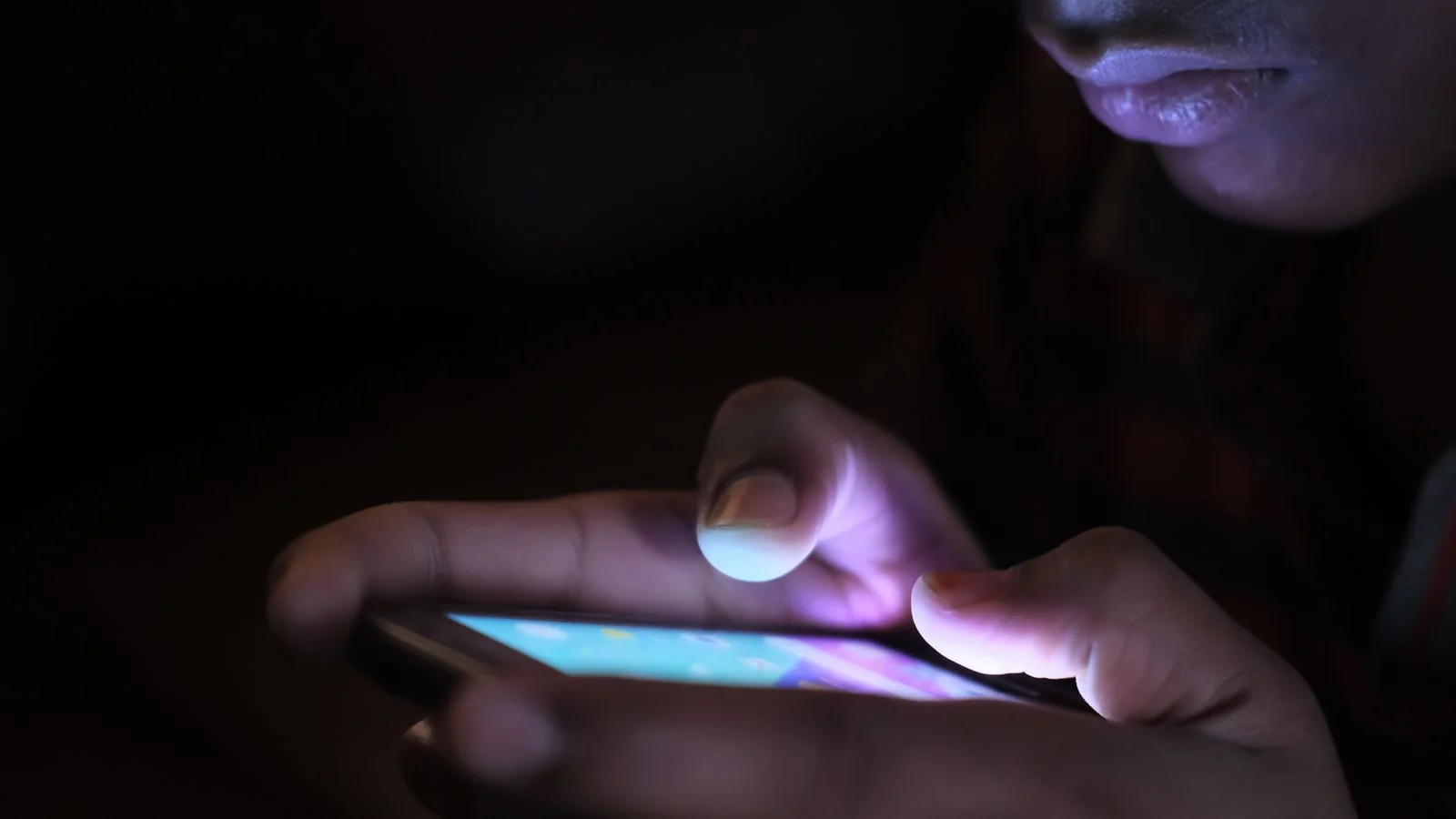 Person scrolling search results on a smartphone in a dark room, looking for someone online