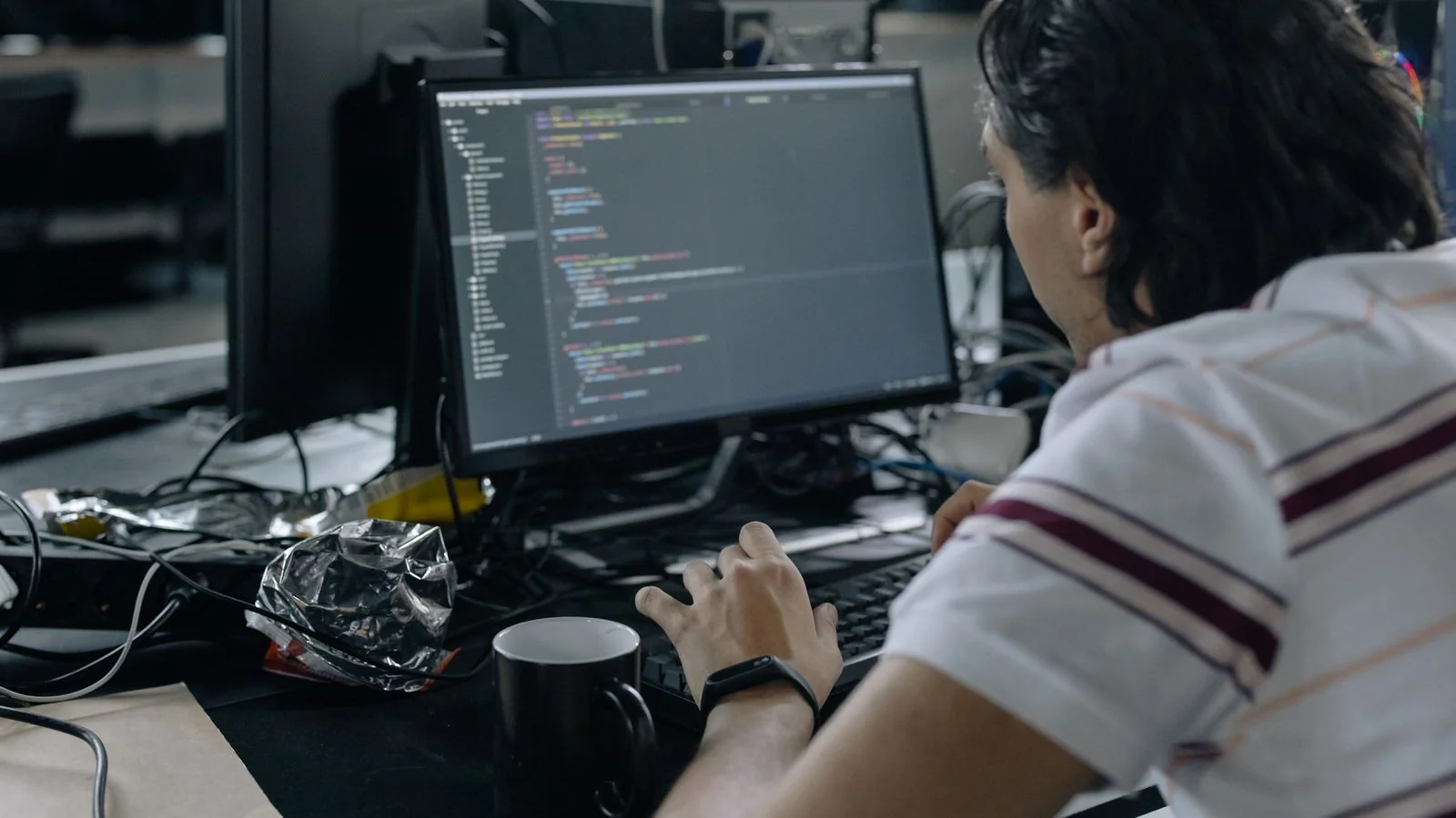 Man writes code at a workstation in a modern office, building JSON-LD markup
