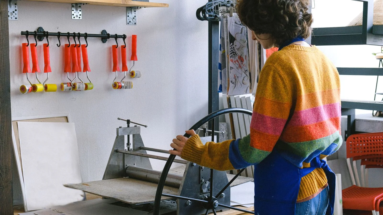 Artisan working a hand-cranked printing press at a studio workbench, the old way books got made
