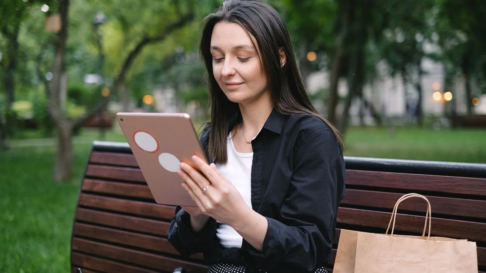 Woman reading on a tablet on a park bench, the attention a paid newsletter is competing for