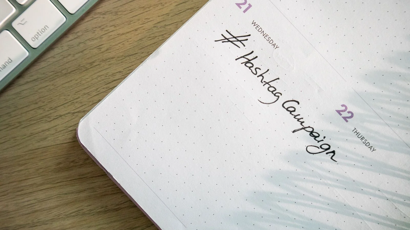 Laptop beside an open planner with social media campaign notes handwritten on the page