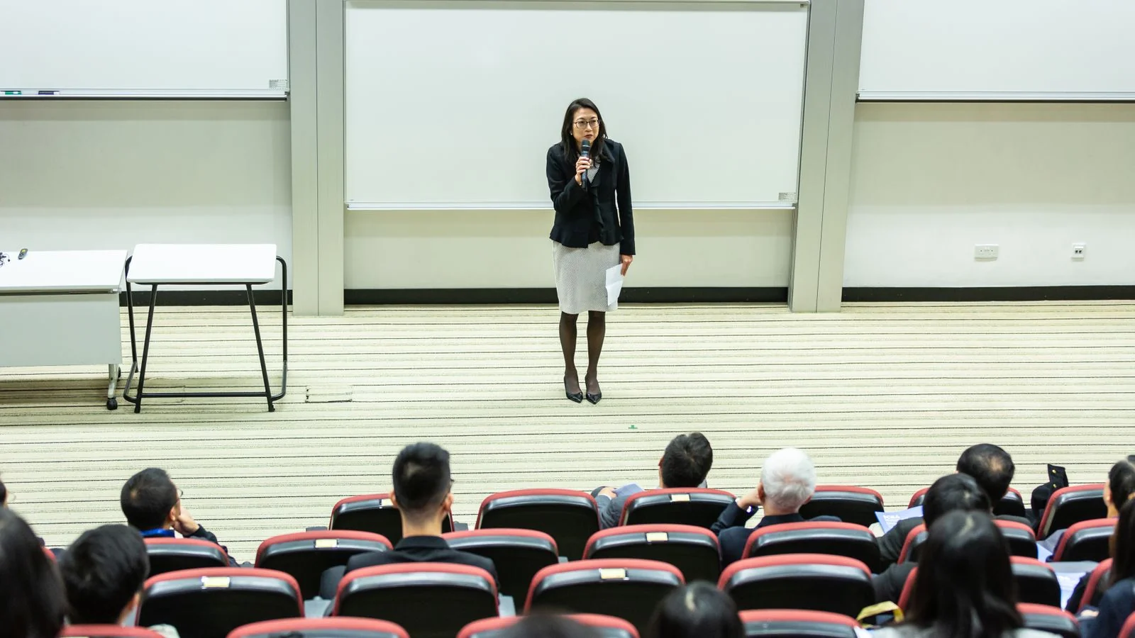 Presenter addressing a full auditorium from the front of the room during an industry session