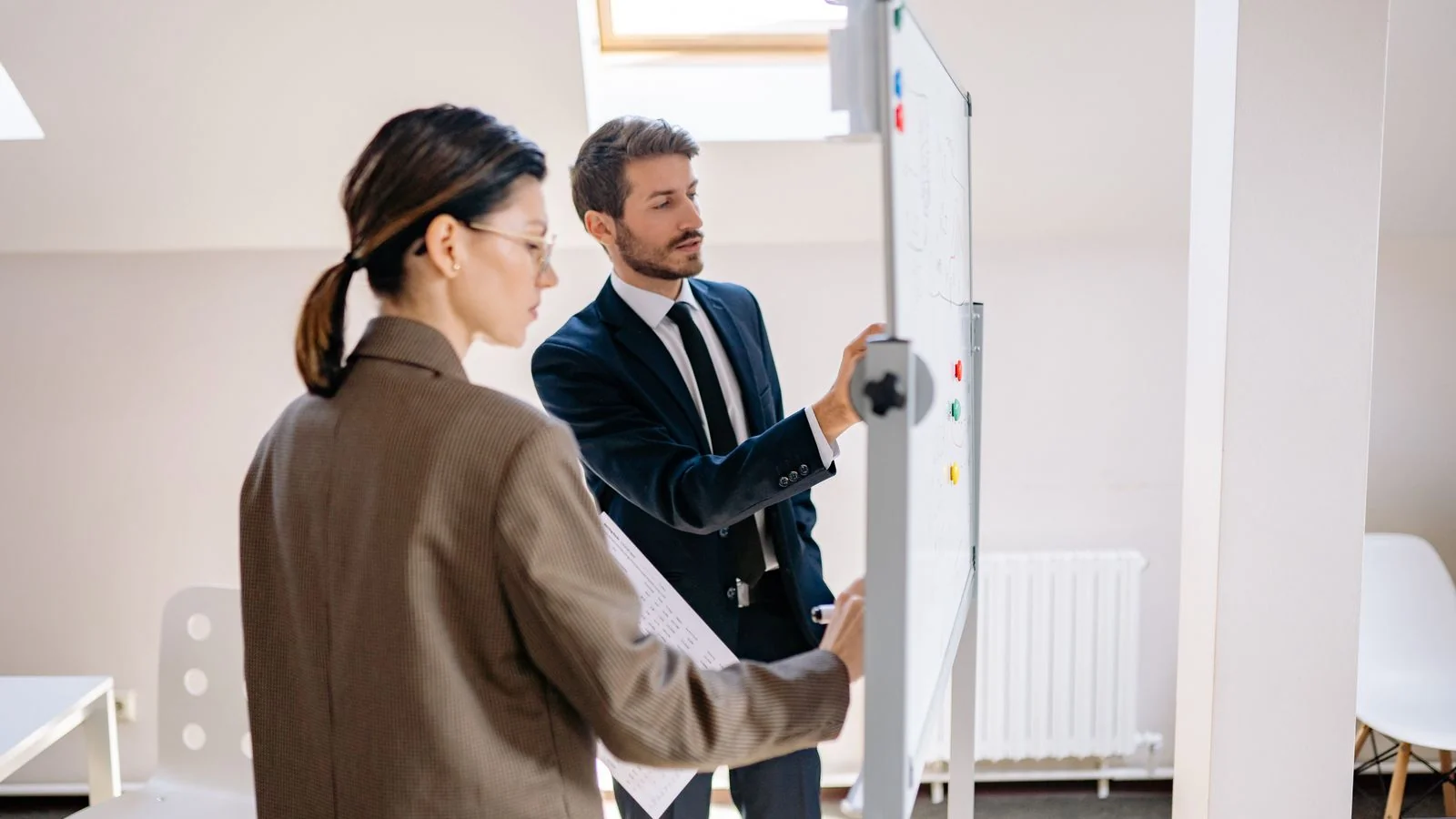Two colleagues writing and reviewing a strategy framework on a whiteboard, representing the cross-lane content planning process in a thought leadership calendar