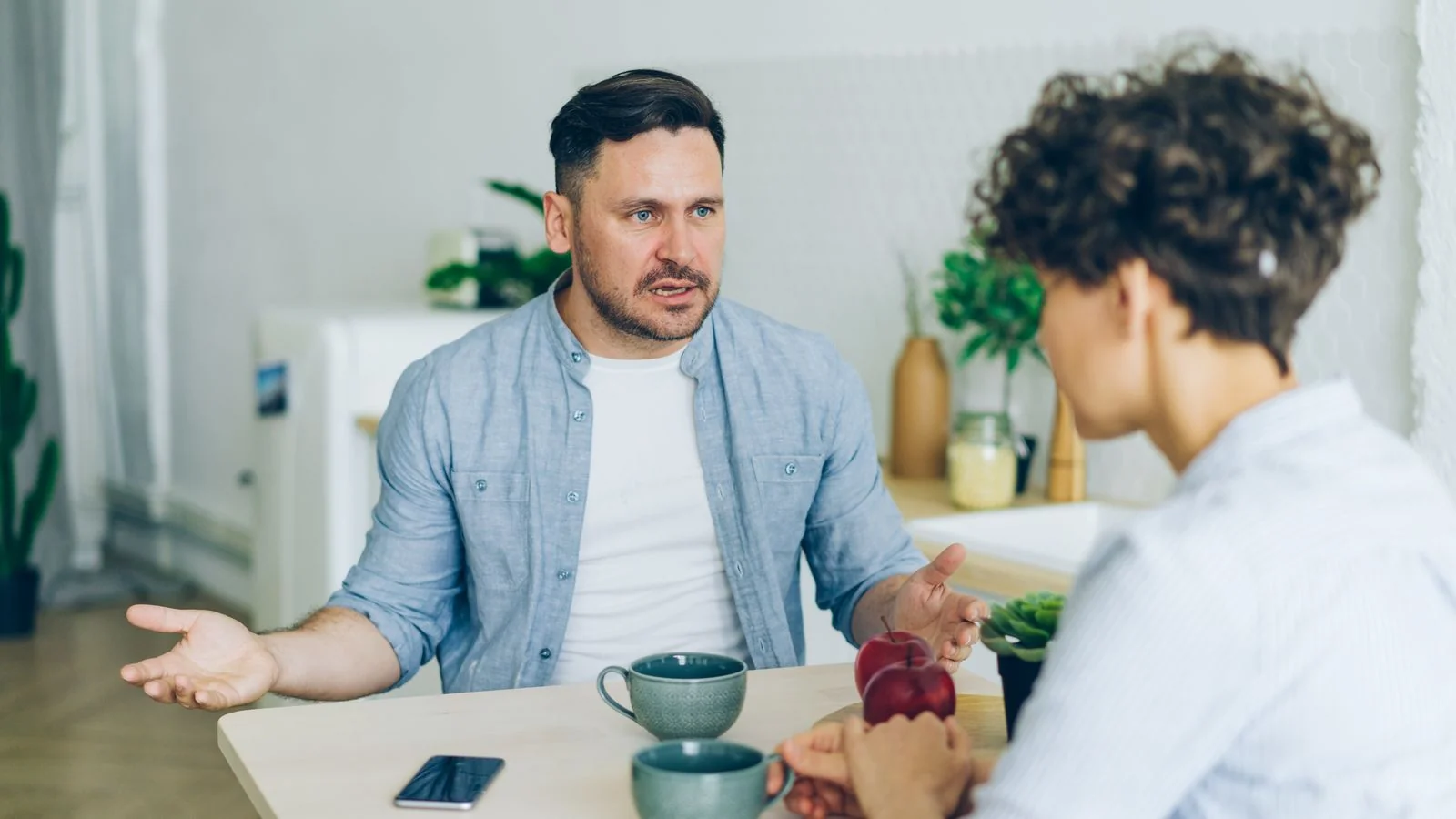 Two people talking over coffee at a kitchen table, where most coaching referrals actually begin
