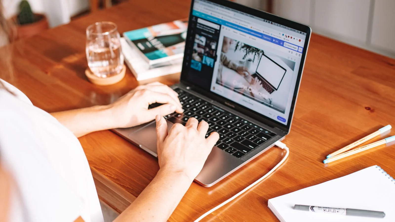 A chiropractor writes patient education notes on a laptop at a wooden desk between appointments.