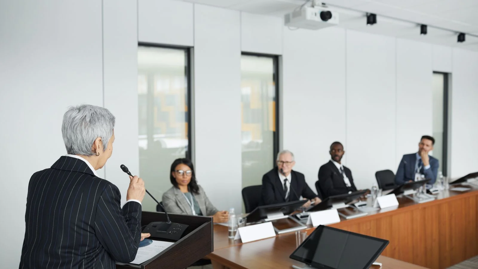 A chiropractor presents a clinical position to fellow professionals seated in a conference room.