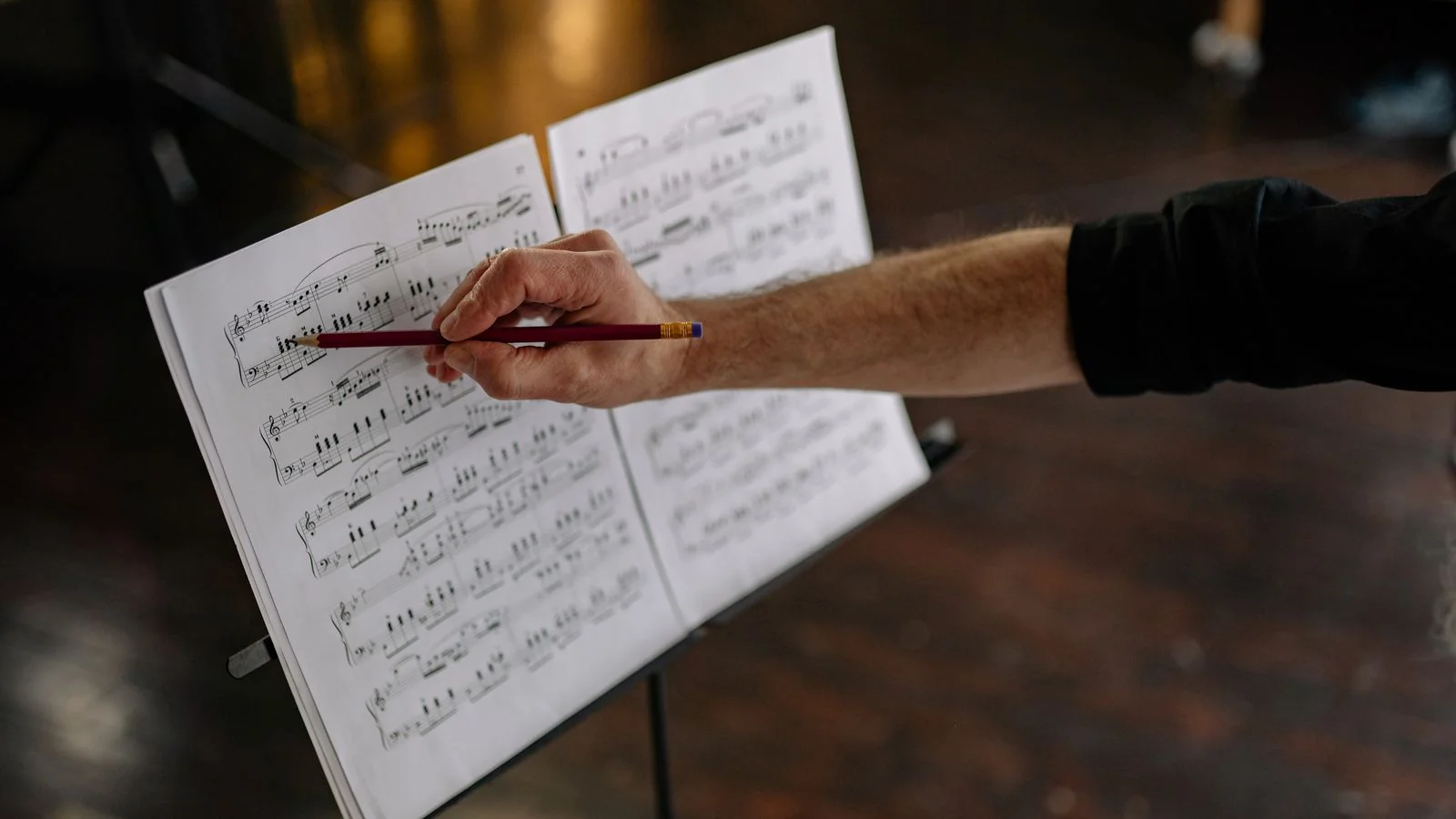 A hand annotating a music sheet with a pencil, the unglamorous work behind a season