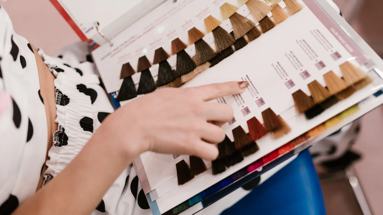 A client choosing between hair colour swatches, the decision that carries more chemistry than anyone in the chair realises
