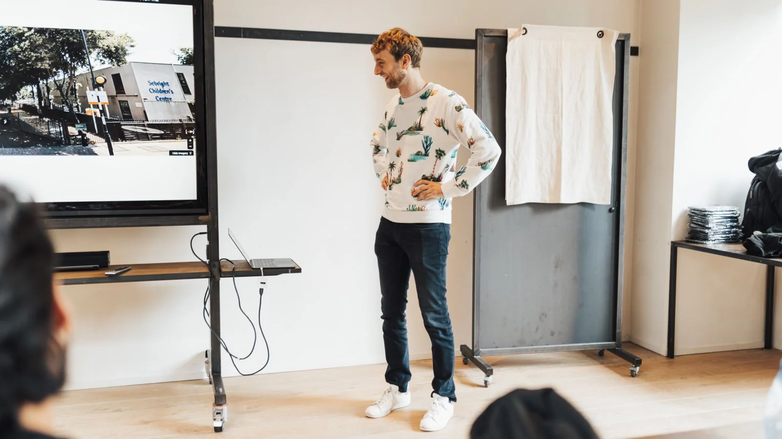 A man presenting to a small audience in a bright office, sharing a point of view rather than a sales pitch.