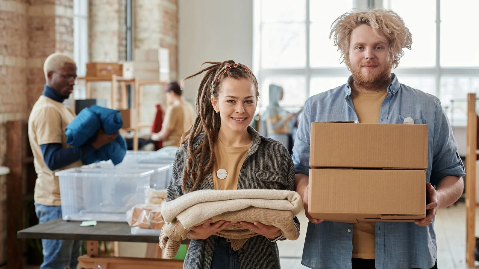 Volunteers holding boxes of donated goods, the reuse side of the story most haulers never tell.