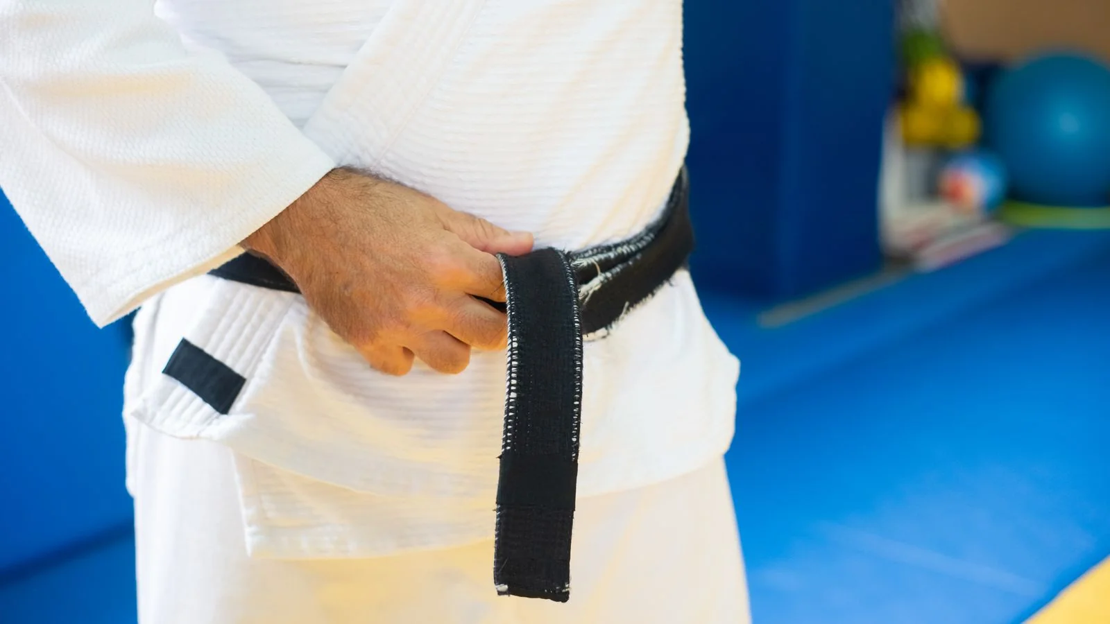 A martial artist tying a black belt, the symbol every parent is trying to evaluate