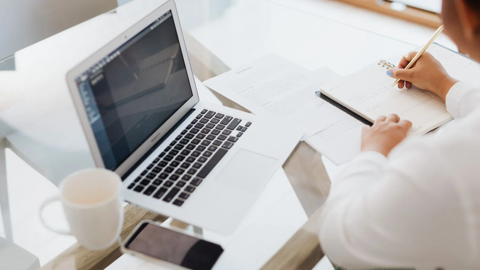 A person writing an article on a laptop at a tidy desk.