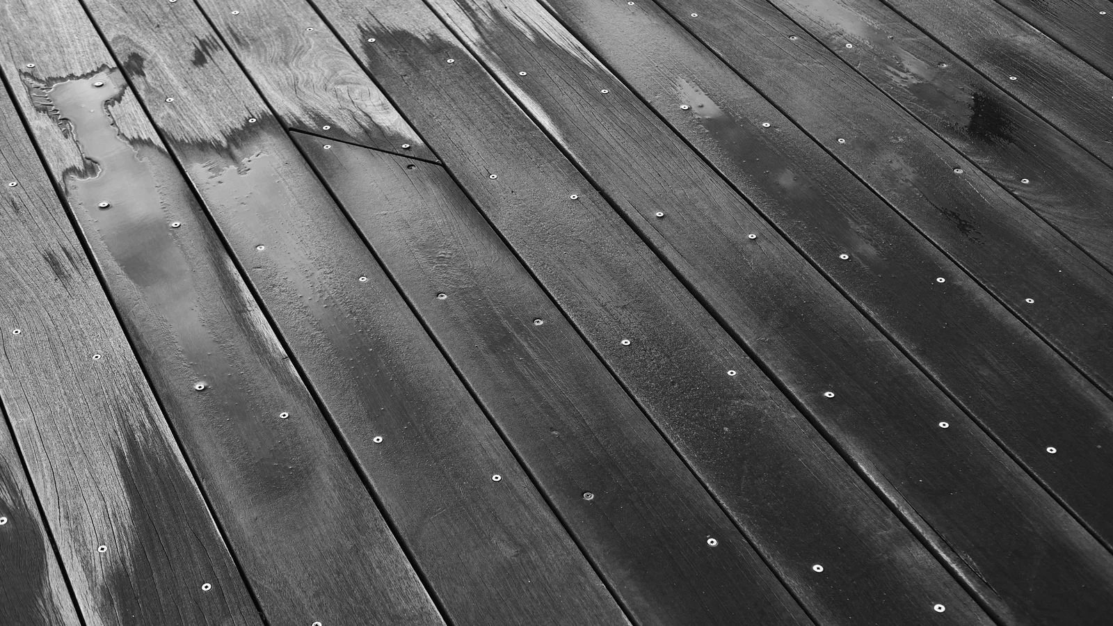 A wet wooden surface showing the grain and texture that the wrong cleaning method can ruin.