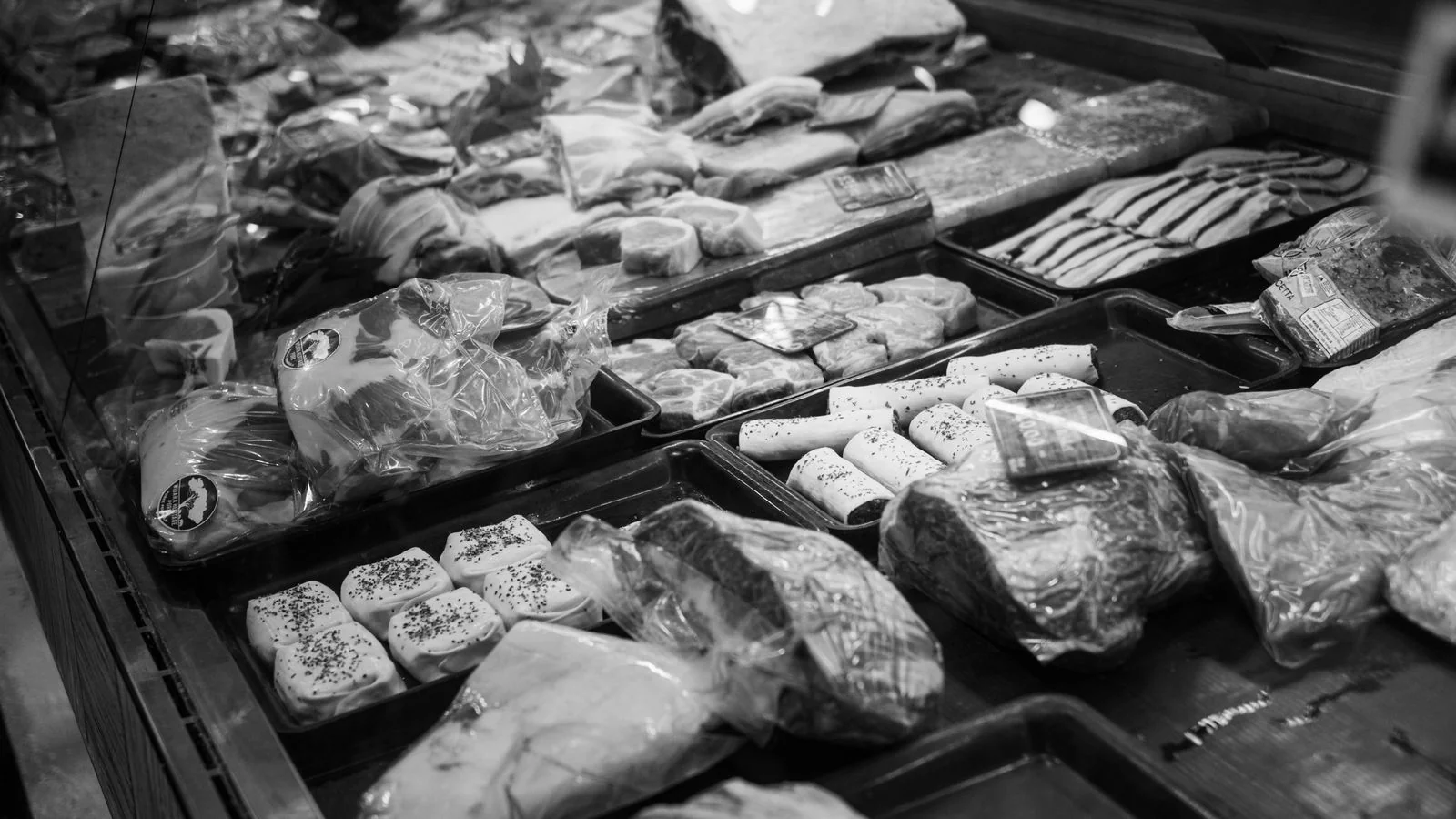 A deli and butcher counter display with packaged goods behind glass.