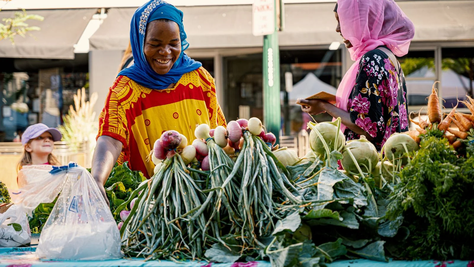 Two people trading at a colorful outdoor produce market stall.