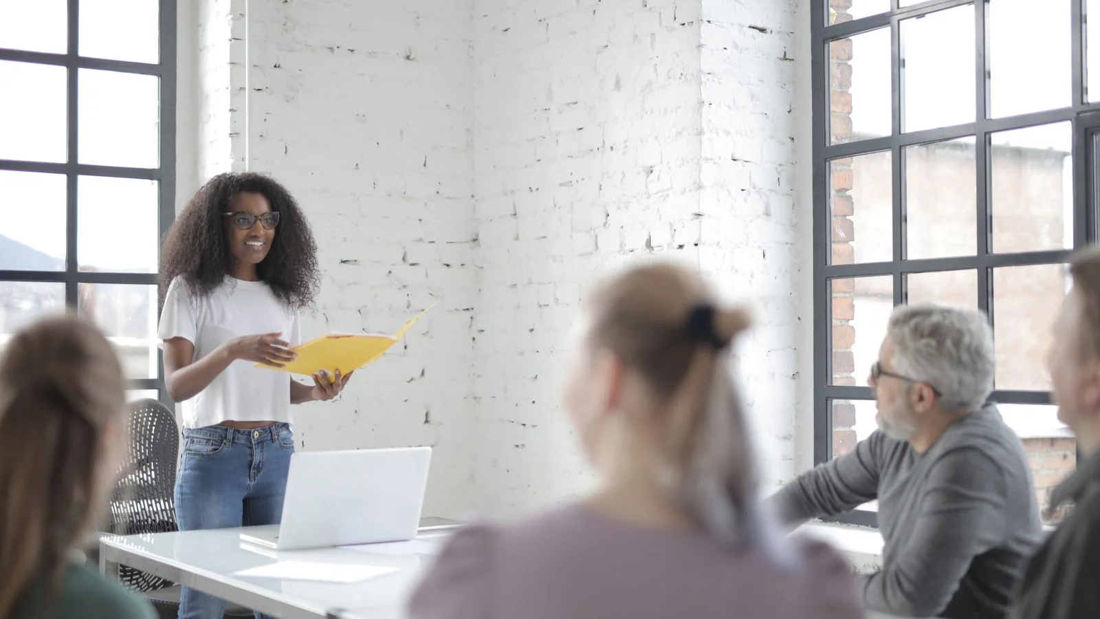 A woman leading a team meeting in an office, presenting ideas to colleagues.