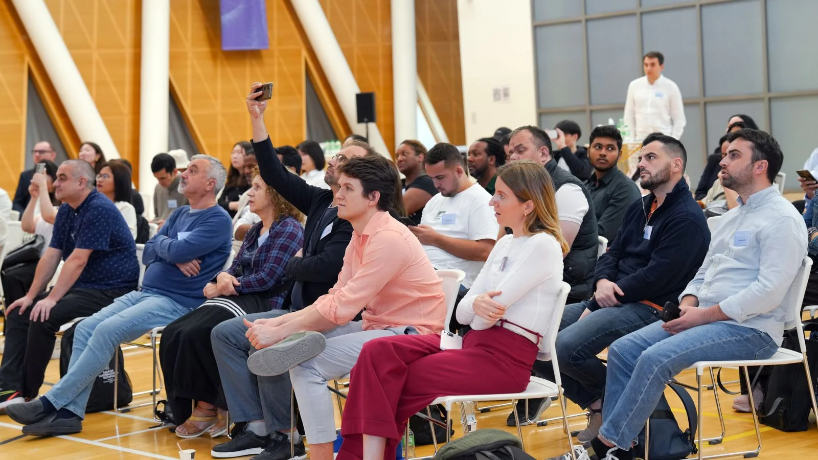 A diverse audience listening attentively during an indoor seminar.