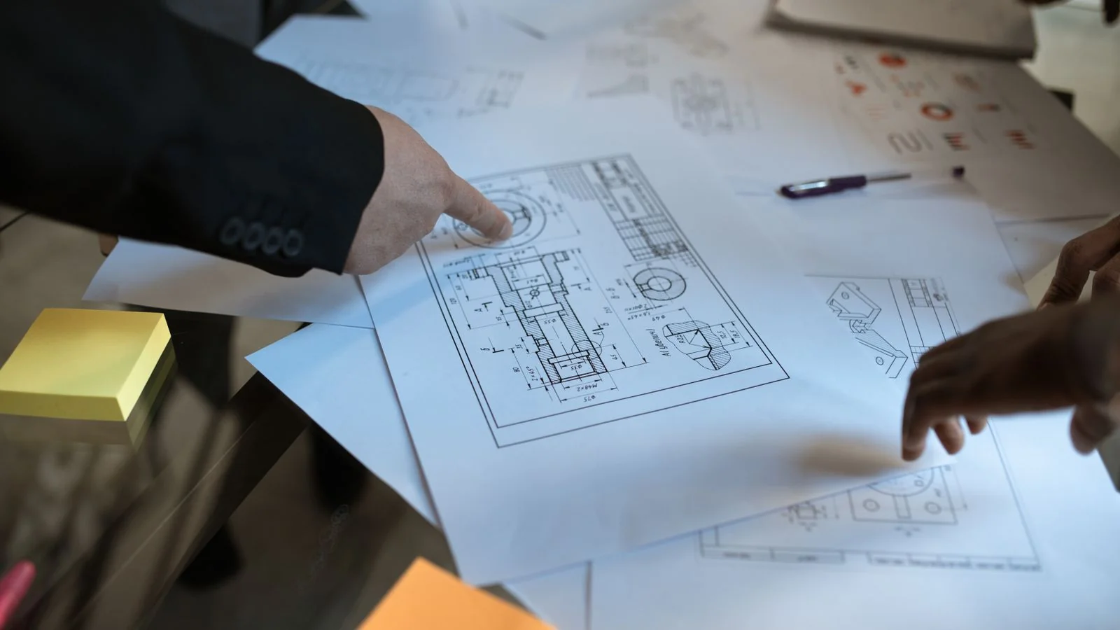 Engineers reviewing a blueprint together, where welding-code knowledge becomes the authority buyers specify.