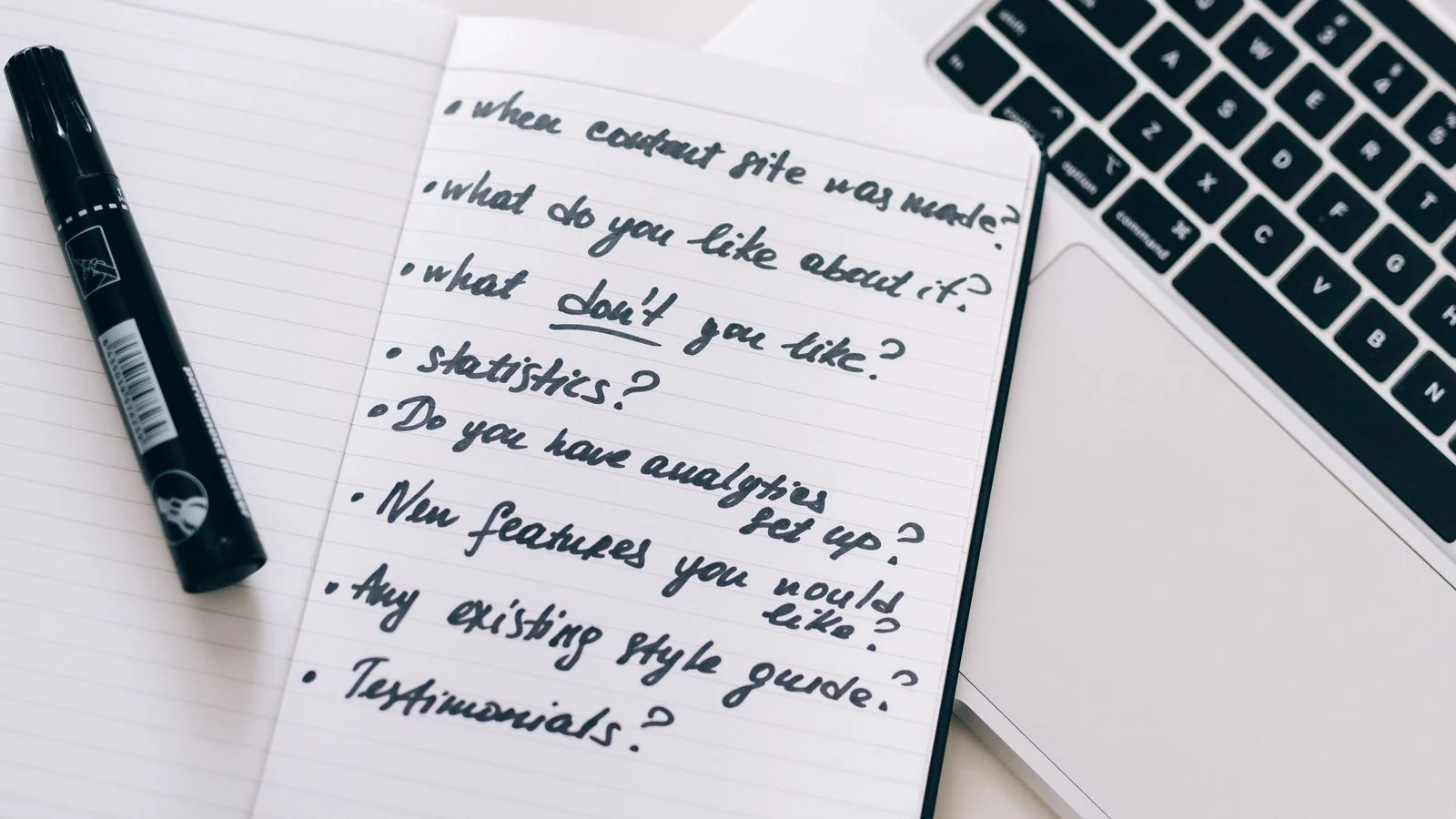 A hand writing notes with a marker over a notebook, the planning that turns scattered posts into a connected cluster
