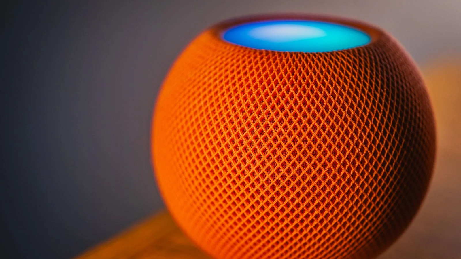 Orange smart speaker glowing with a blue light ring, the hardware Alexa and Gemini now run on