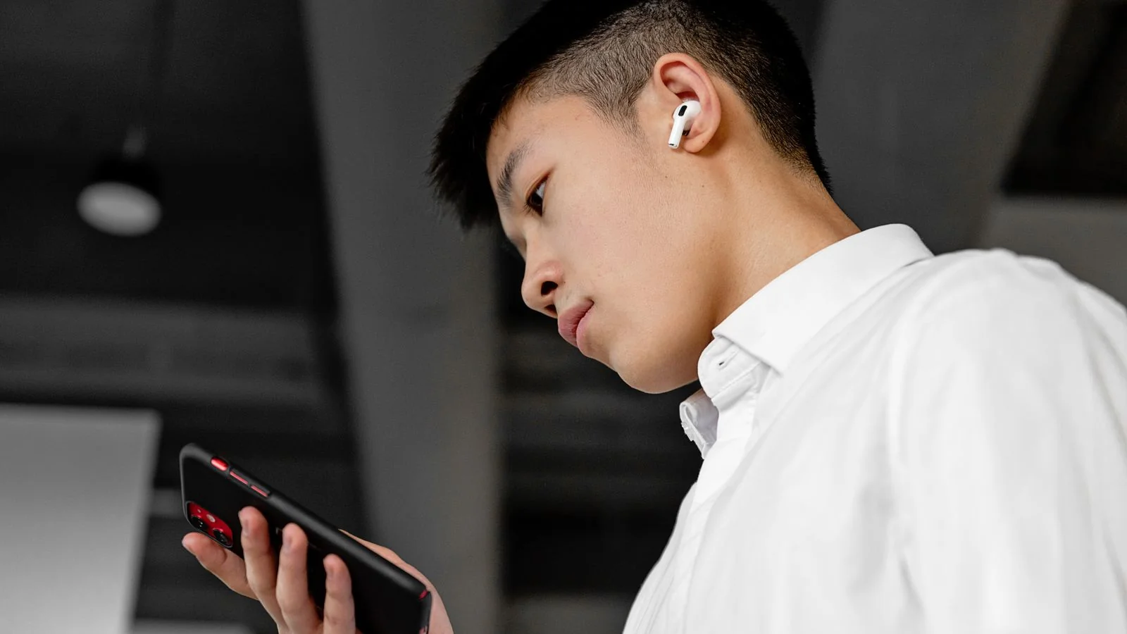 Young man wearing wireless earbuds and talking to a phone assistant, the new face of voice search