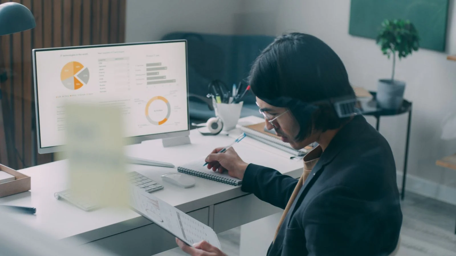 Professional comparing printed charts against an analytics screen at a modern desk