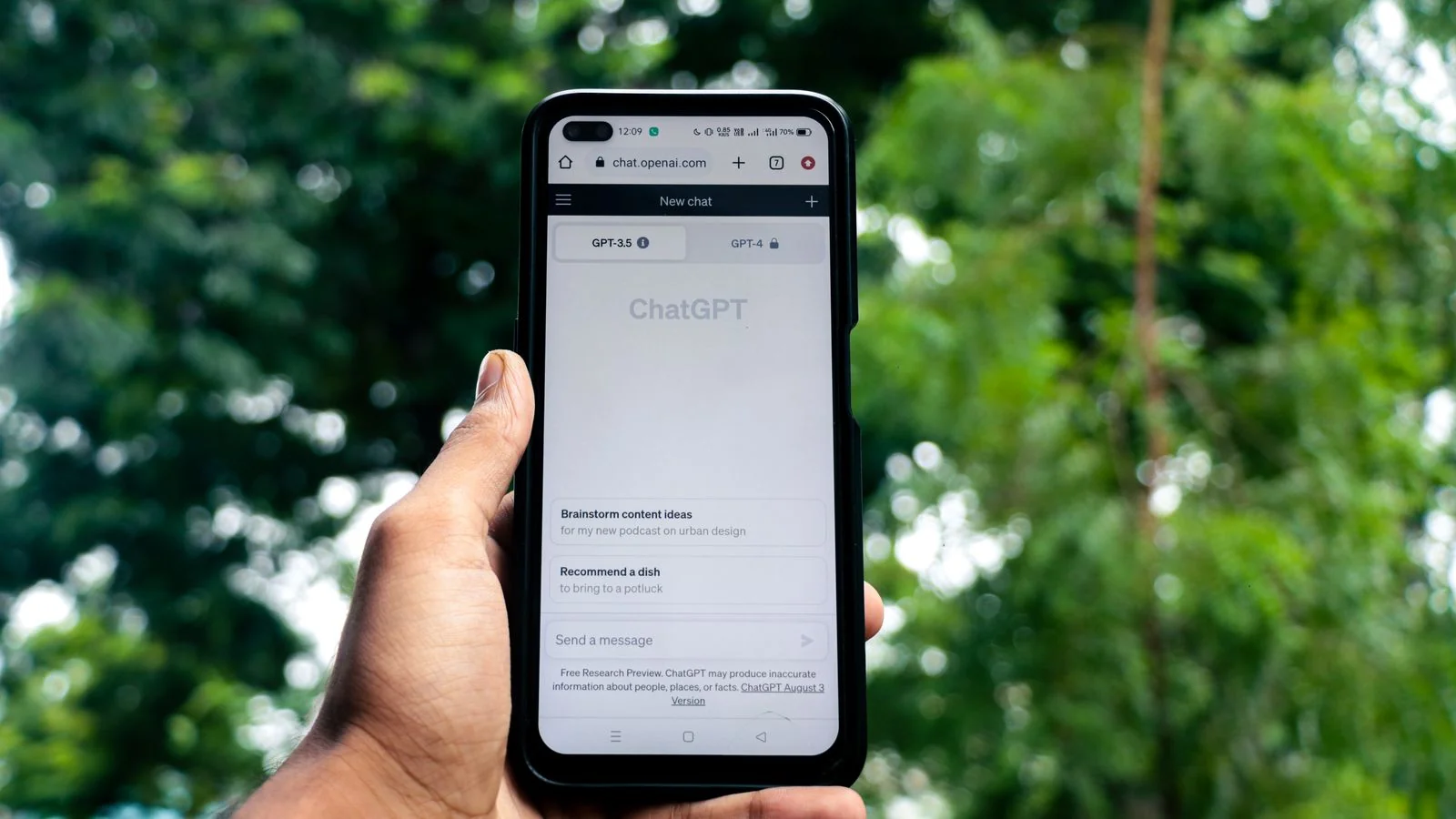 Hand holding a smartphone showing ChatGPT outdoors, the other place people now look you up