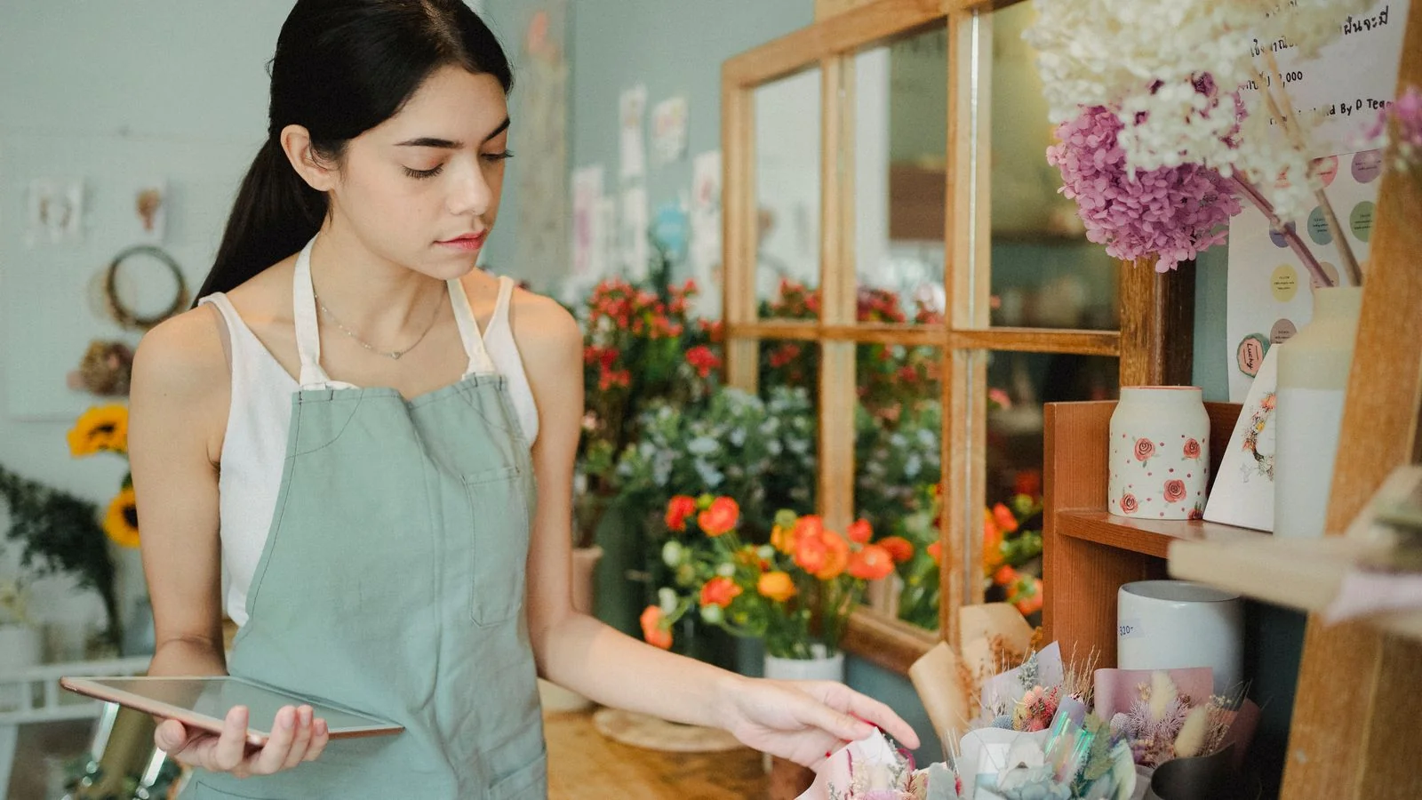 Woman florist checking an order on a tablet in her flower shop, one of 14.5 million US women-owned businesses