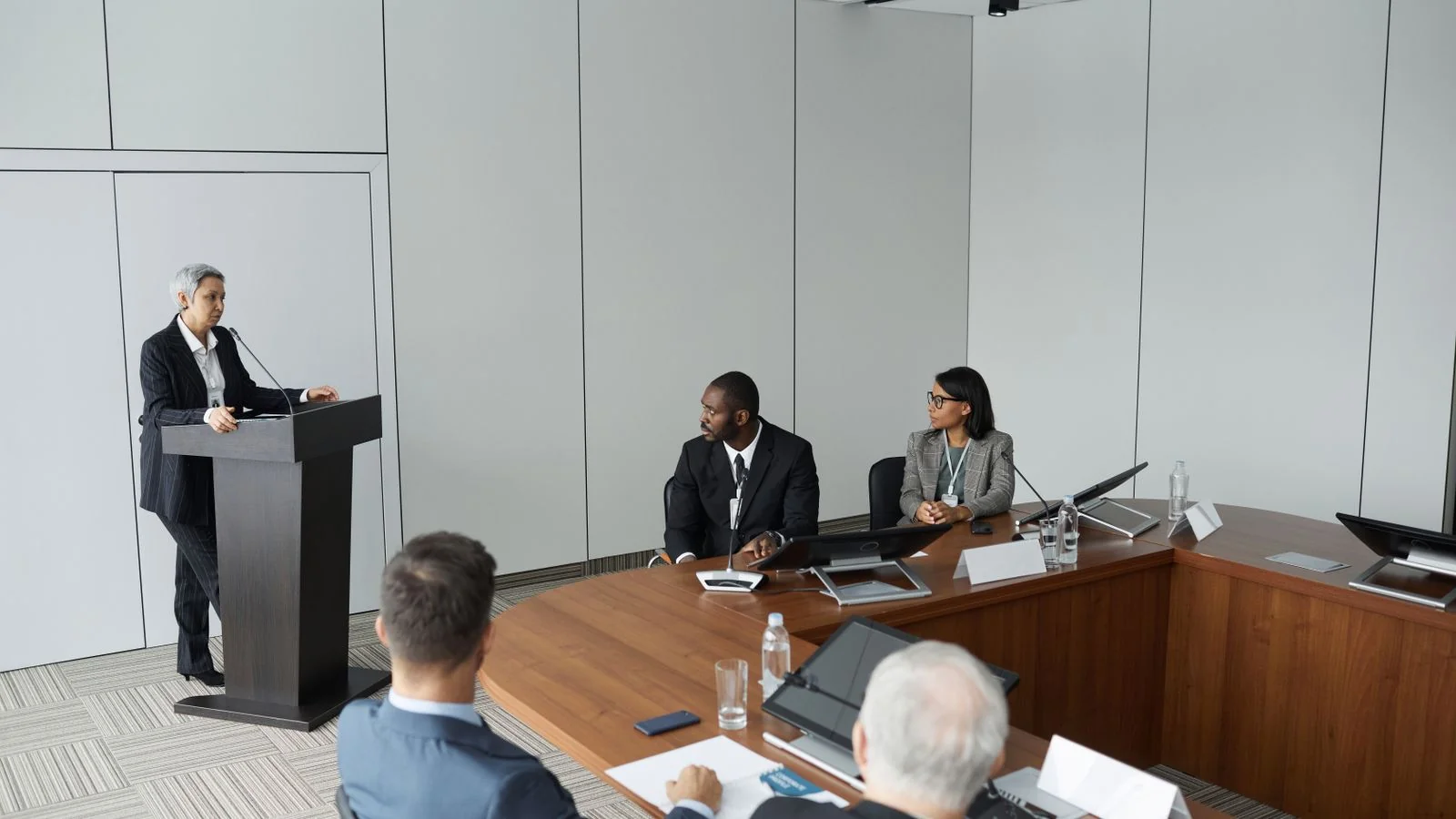Woman speaking at a podium to a room of professionals, the kind of stage that comes before a raise