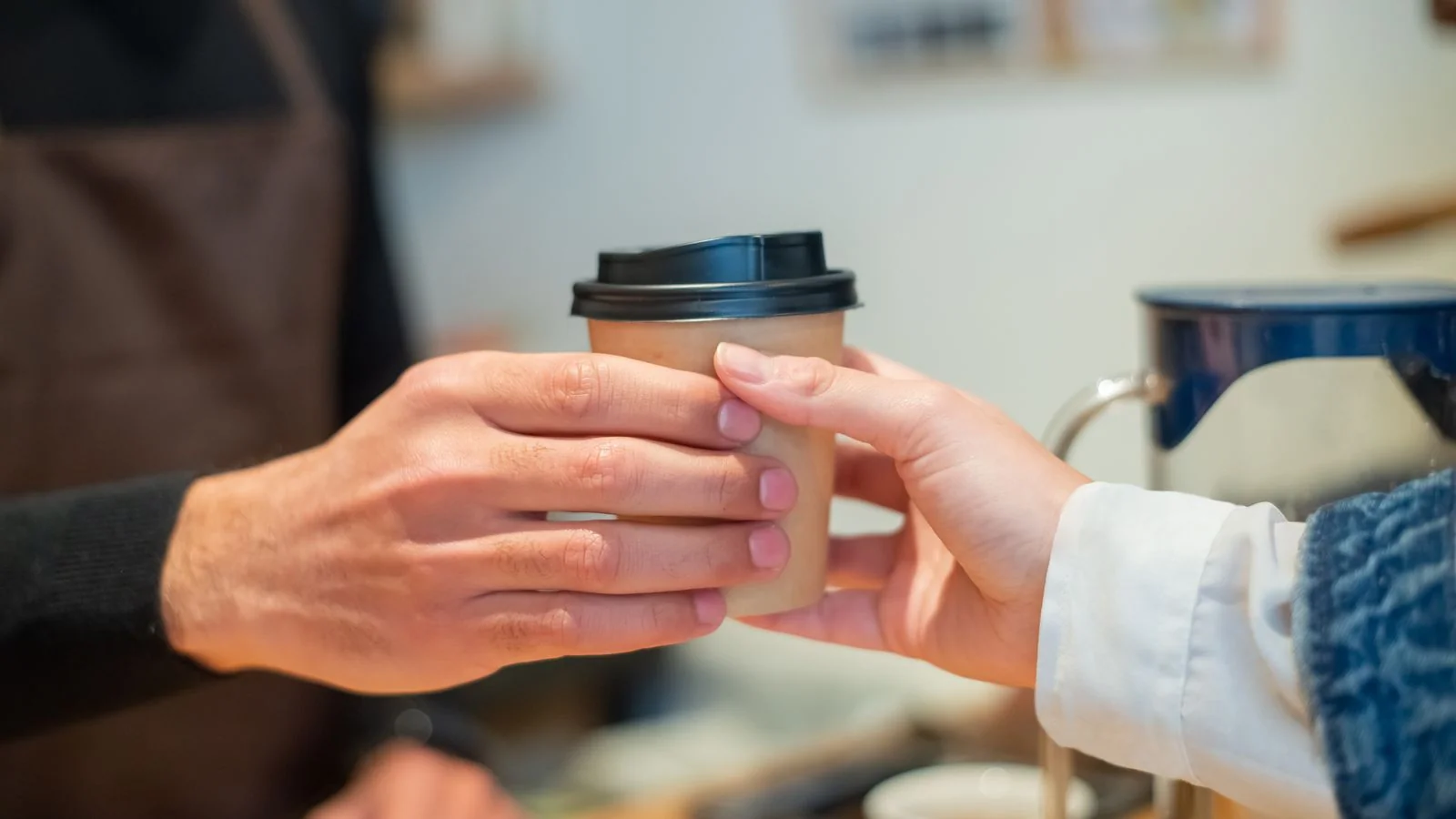Barista handing a coffee cup across the counter, the local transaction Yelp advertising is priced against